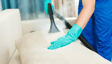 An employee of a cleaning company provides a chemical and steam cleaning service for the sofa. Steam cleaner
